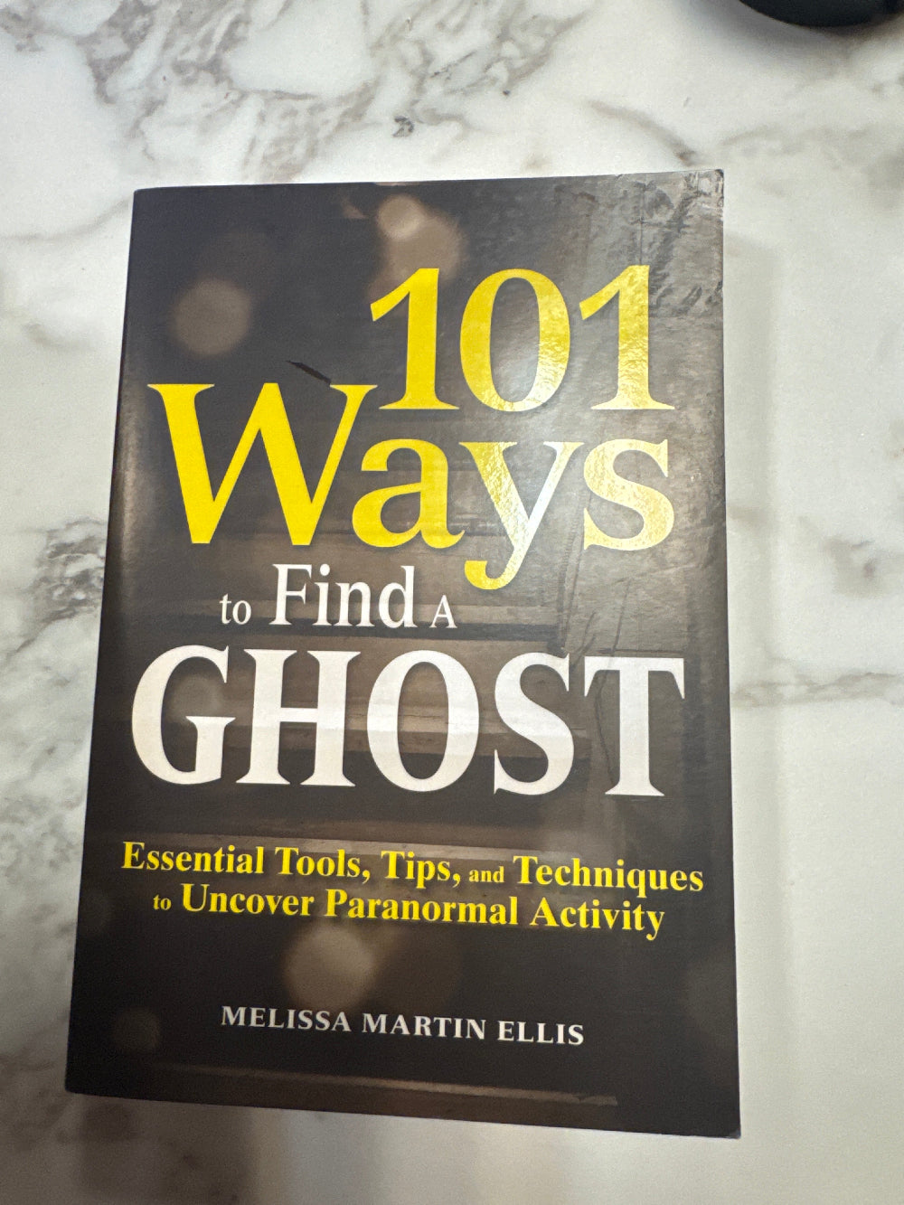 Book titled '101 Ways to Find a Ghost' on a marble surface