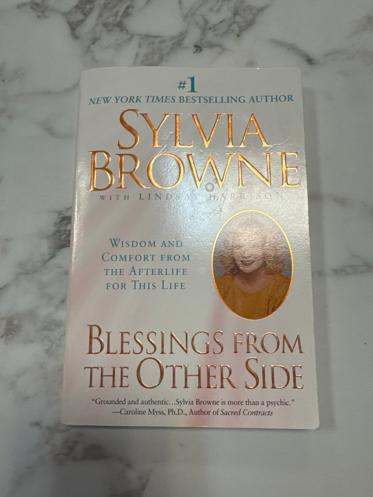 Blessings from the Other Side softcover book by Sylvia Browne with gold foil lettering and teal text on marble