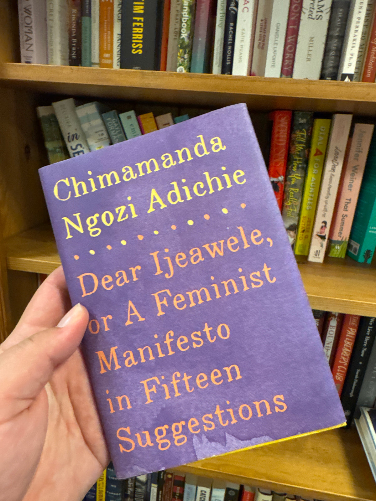 Purple hardcover book Dear Ijeawele by Chimamanda Ngozi Adichie held in hand