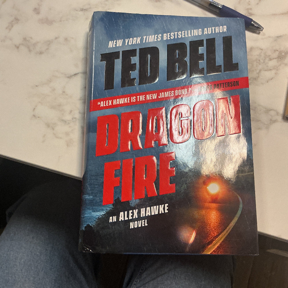 Book titled 'Dragon Fire' by Ted Bell on a marble surface