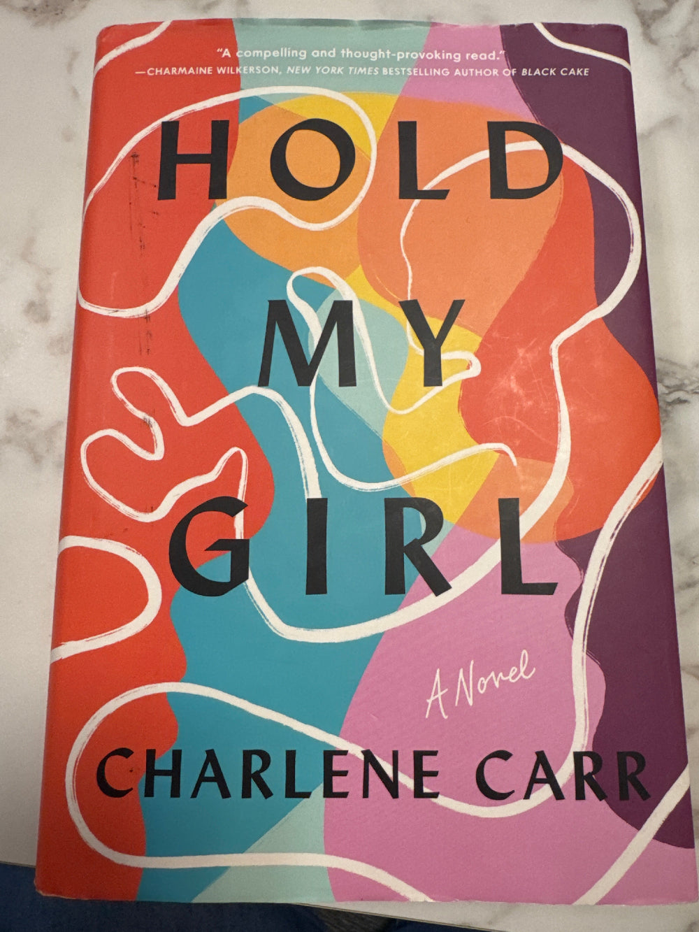 Book cover of 'Hold My Girl' by Charlene Carr on a marble surface
