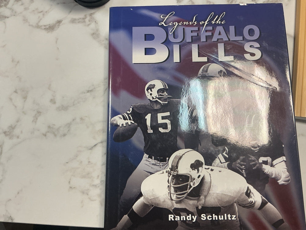Book titled 'Legends of the Buffalo Bills' by Randy Schultz on a marble surface.