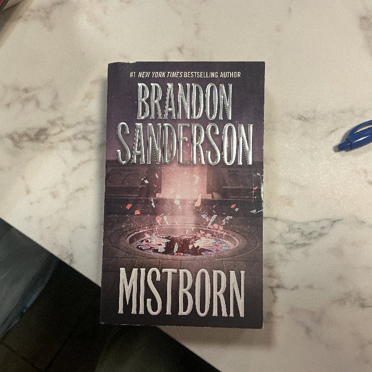 Book titled 'Mistborn' by Brandon Sanderson on a marble surface.