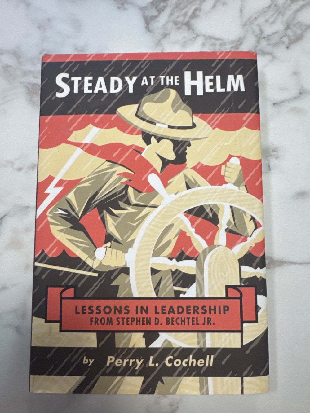 Book titled 'Steady at the Helm' on a marble surface