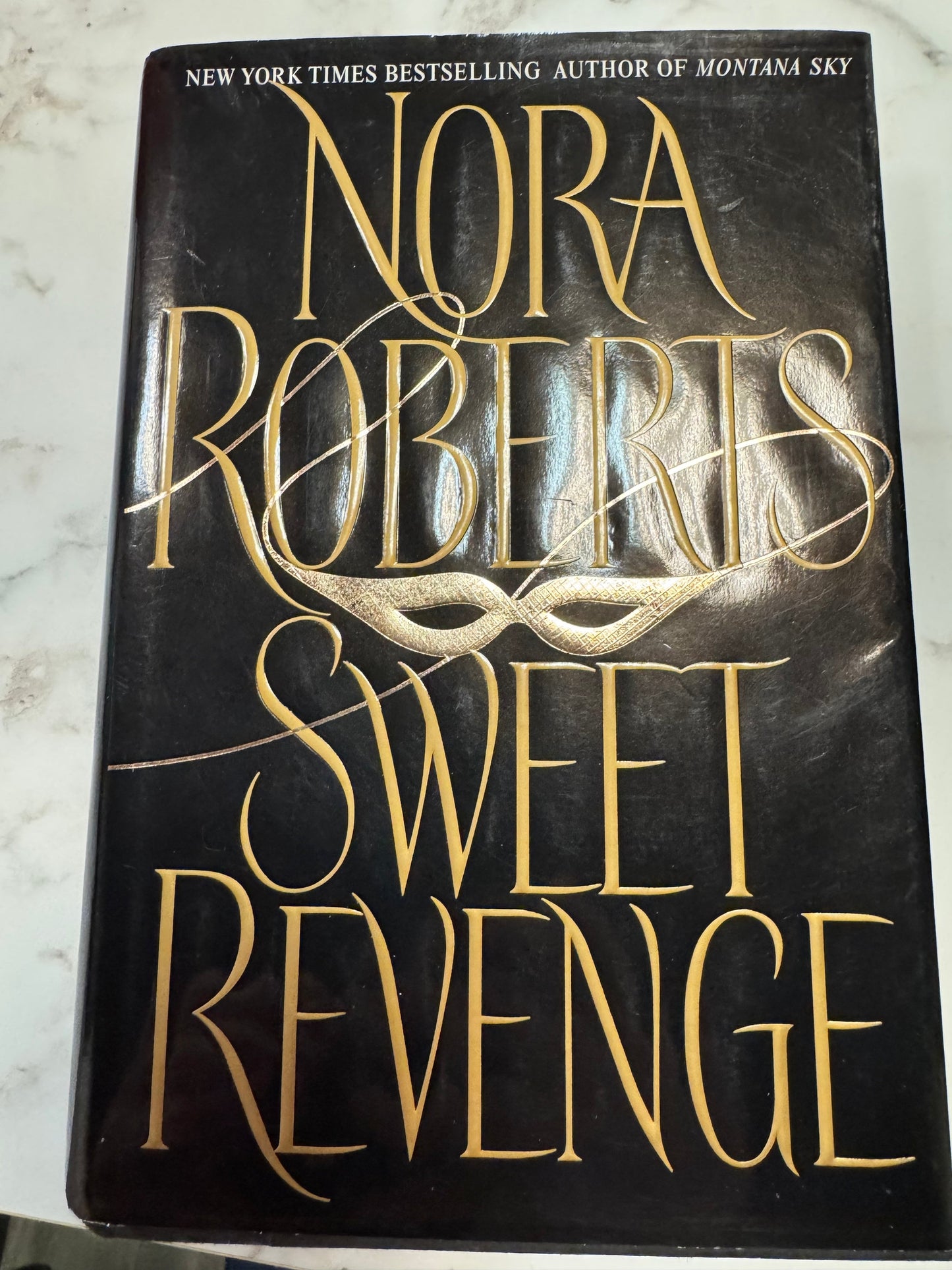 Sweet Revenge hardcover book by Nora Roberts with gold mask cover design