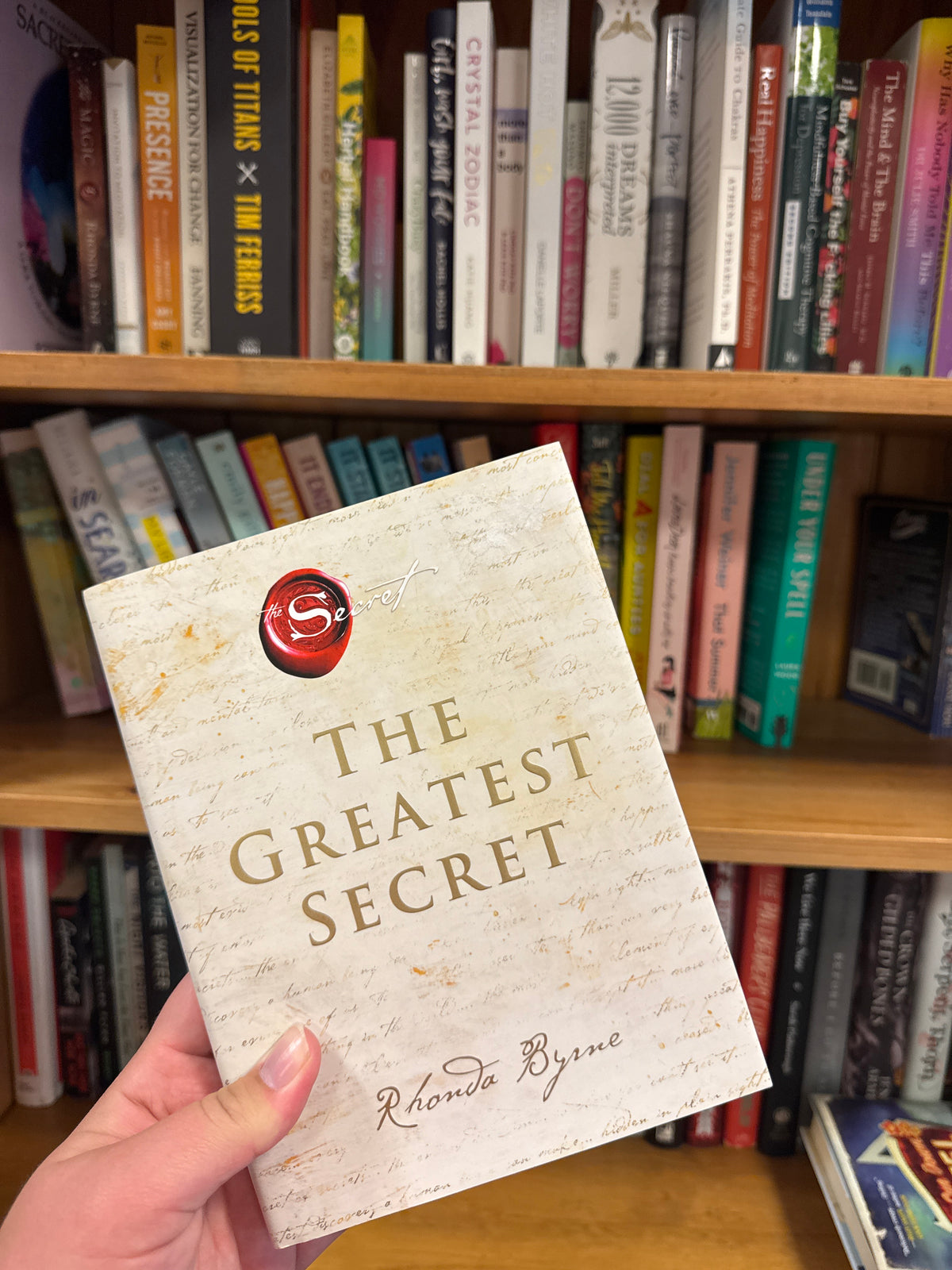 The Greatest Secret paperback book by Rhonda Byrne with cream cover and gold title
