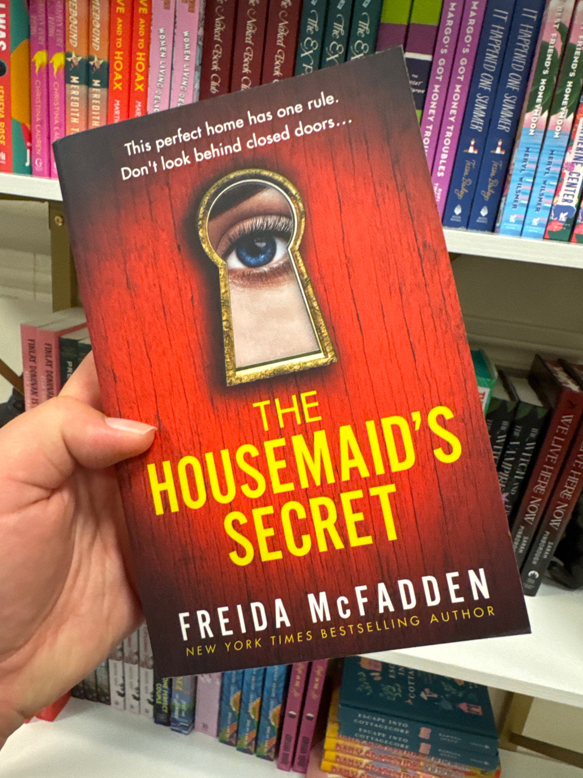 The Housemaid's Secret paperback by Freida McFadden with red wood-grain cover and gold keyhole design