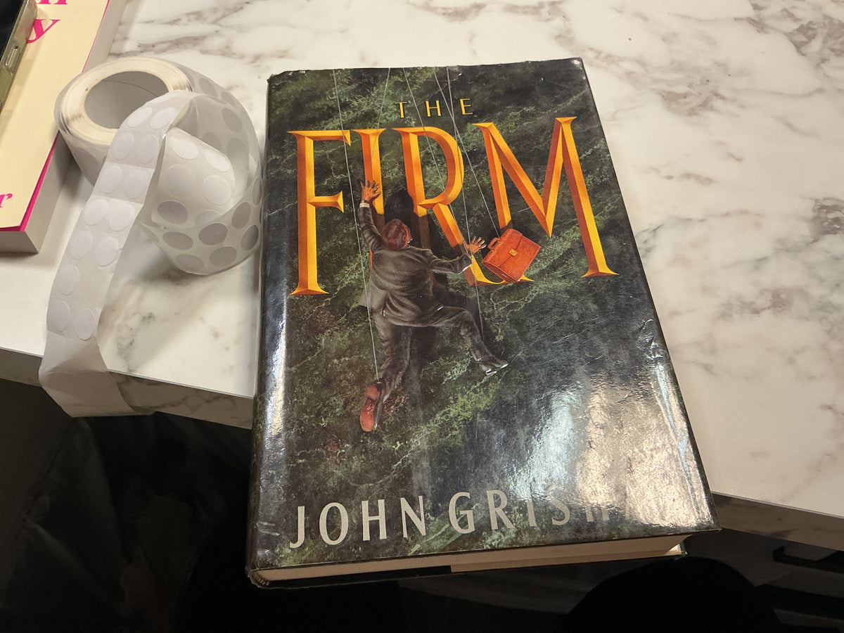 The Firm hardcover book by John Grisham with dark green textured cover and orange title text