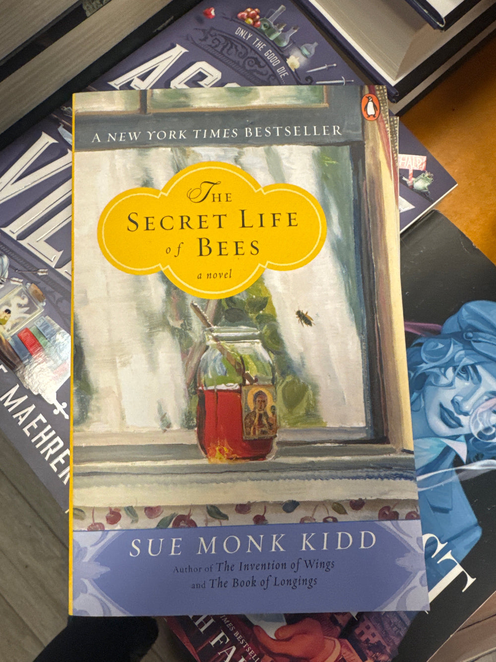 Book titled 'The Secret Life of Bees' by Sue Monk Kidd on a surface with other books.