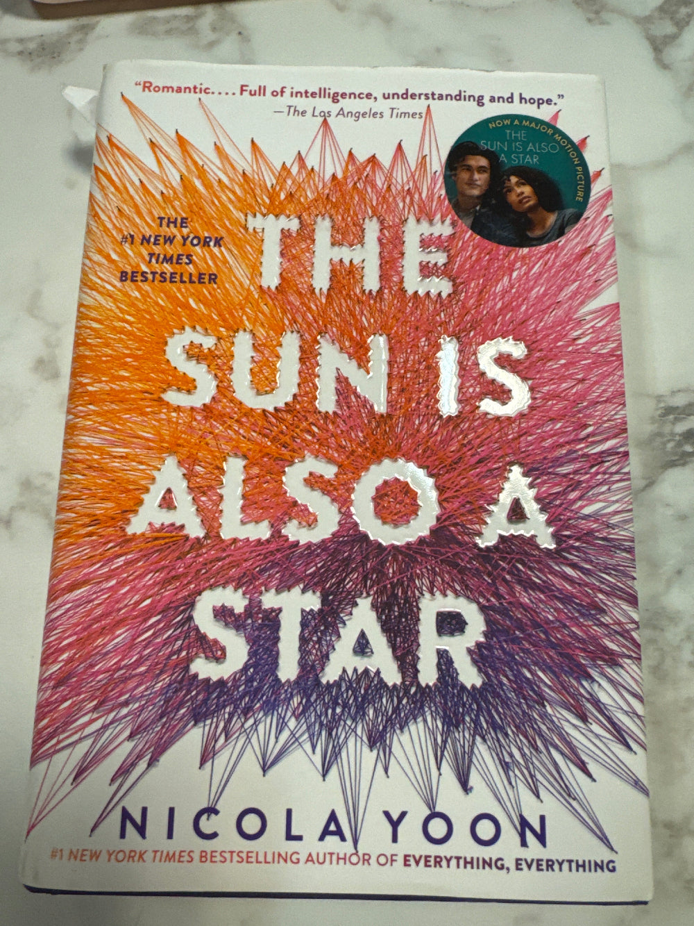 Book cover of 'The Sun is Also a Star' by Nicola Yoon on a marble surface