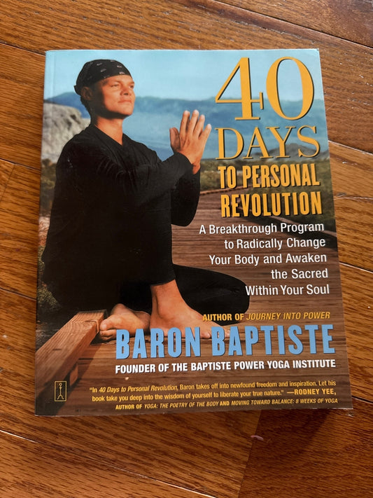 Hardcover book 40 Days to Personal Revolution by Baron Baptiste on wooden floor