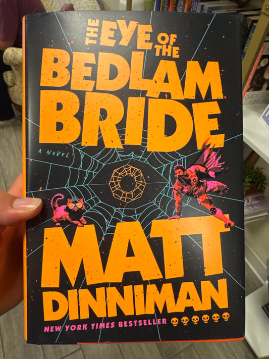 The Eye of the Bedlam Bride hardcover book by Matt Dinniman with orange title and teal spiderweb design
