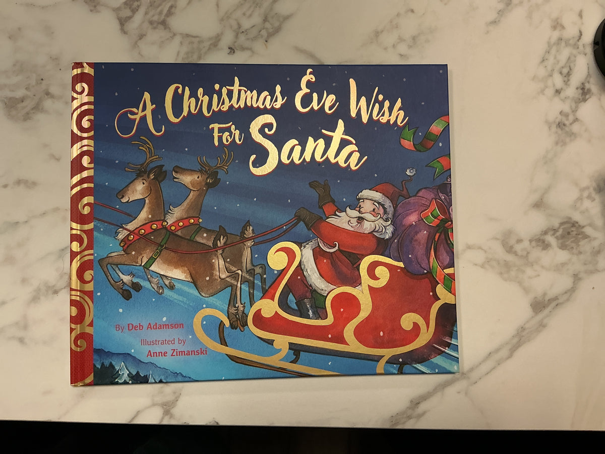 A Christmas Eve Wish for Santa hardcover children's book by Deb Adamson, gold cursive title on dark blue snowy cover with Santa in sleigh