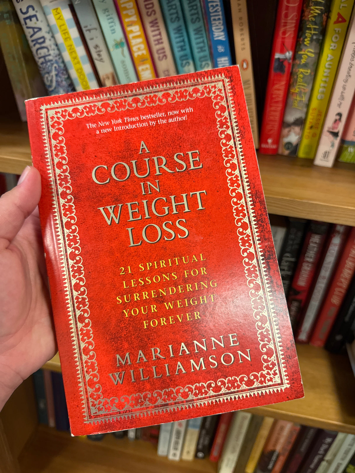 Red hardcover A Course in Weight Loss by Marianne Williamson with gold embossed text