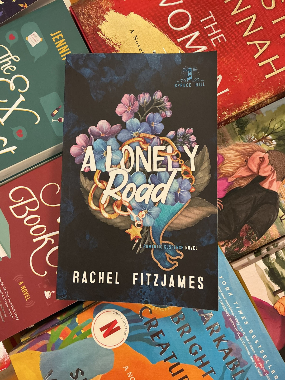 A Lonely Road hardcover book by Rachel Fitzjames with dark cover and floral wreath design