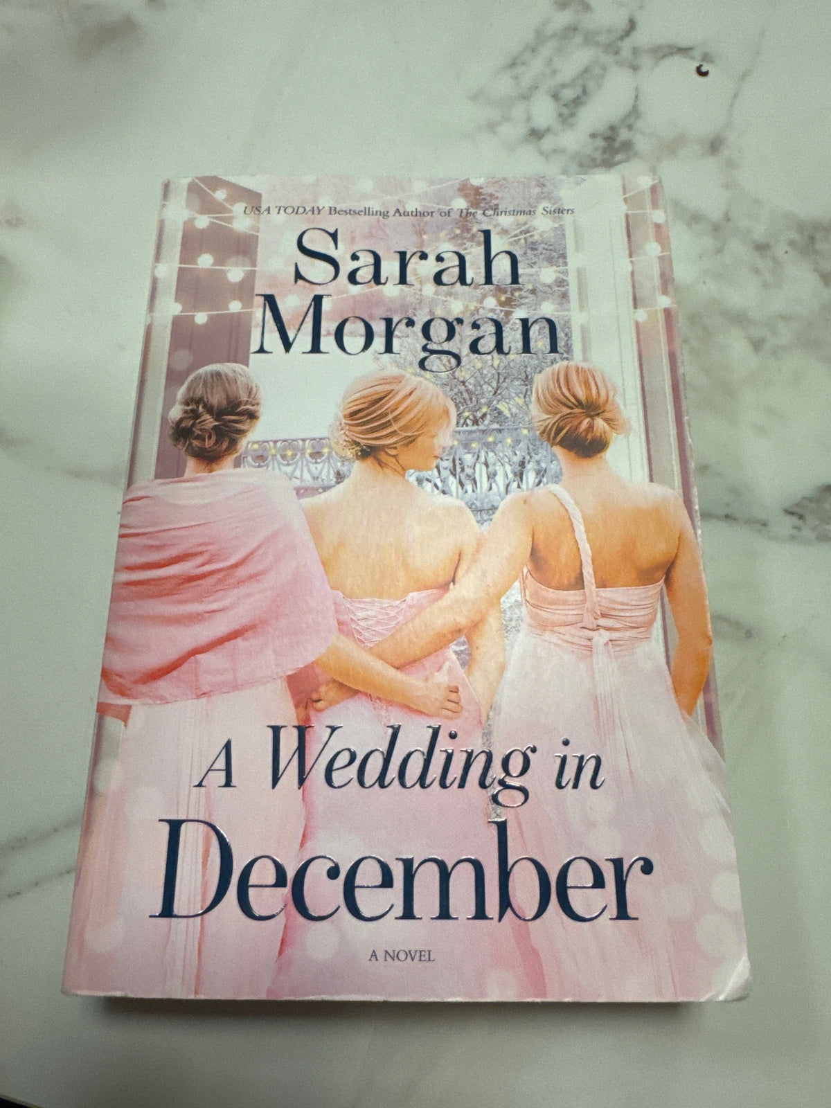 A Wedding in December hardcover novel by Sarah Morgan featuring three women in pink dresses on cover