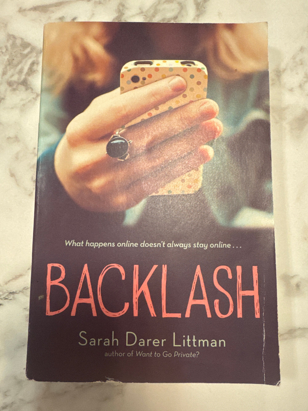 Book cover of 'Backlash' by Sarah Darer Littman on a marble surface