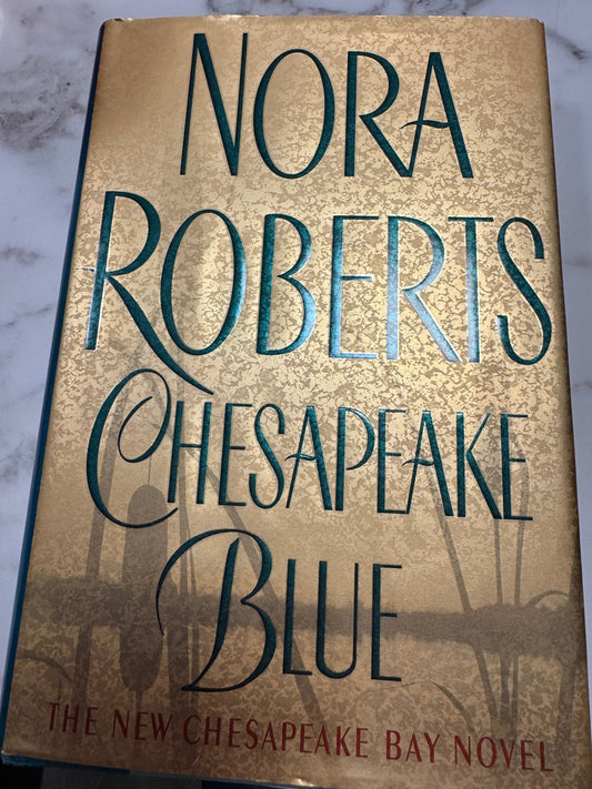 Chesapeake Blue hardcover book by Nora Roberts with gold textured cover and teal typography