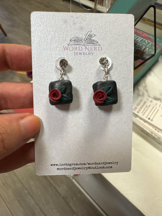 Black square clay dangle earrings with red rose and green leaf details on silver rhinestone studs