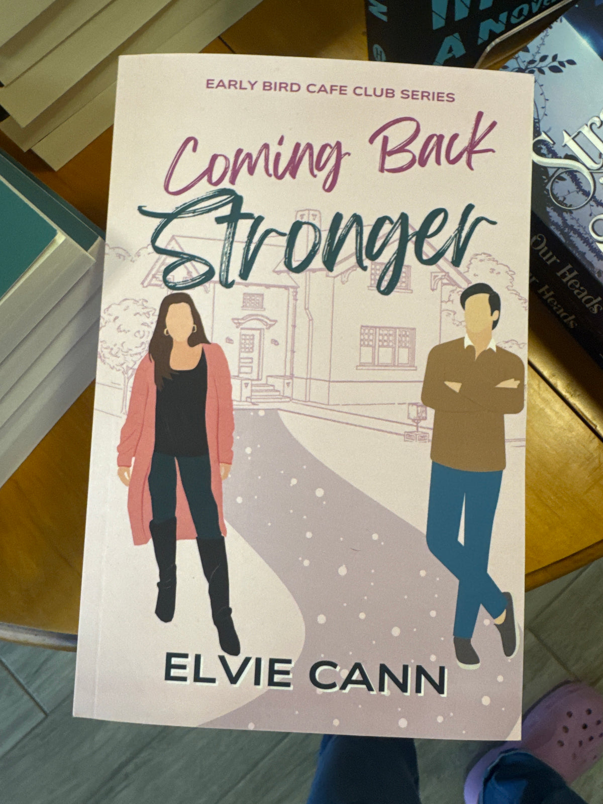 Coming Back Stronger paperback romance novel by Elvie Cann, pink and teal cover with illustrated couple