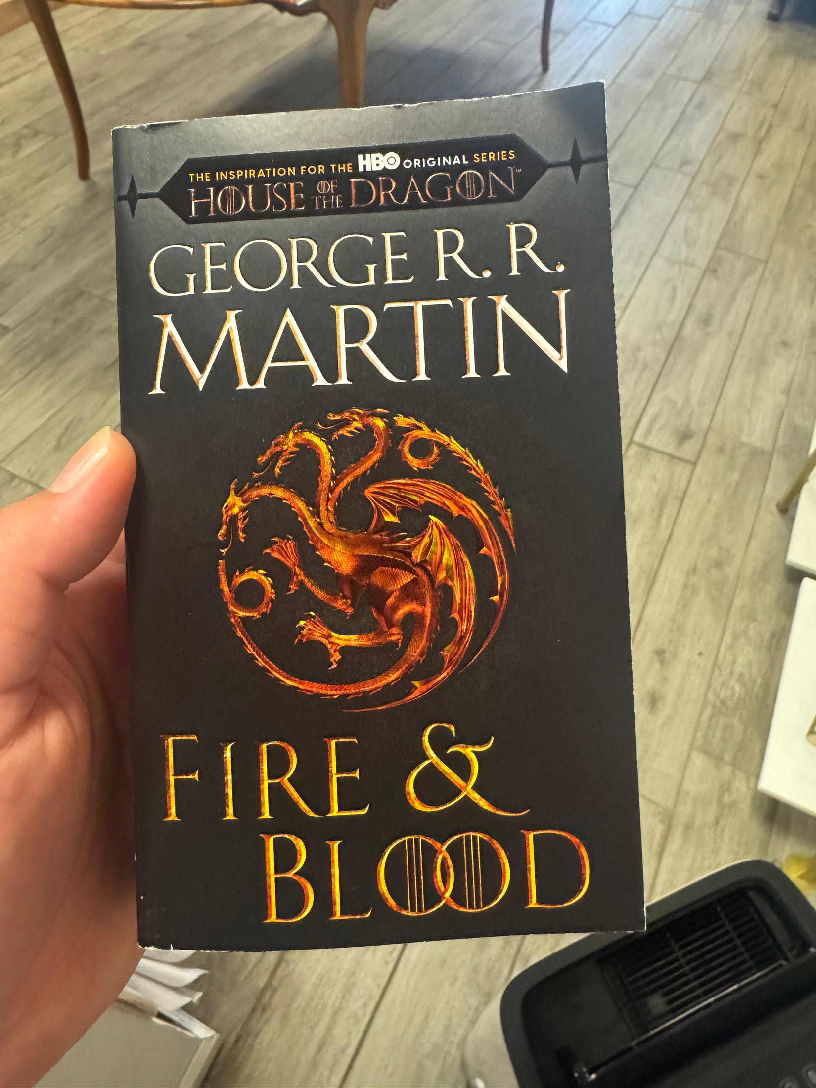 A hand holding a paperback copy of George R.R.