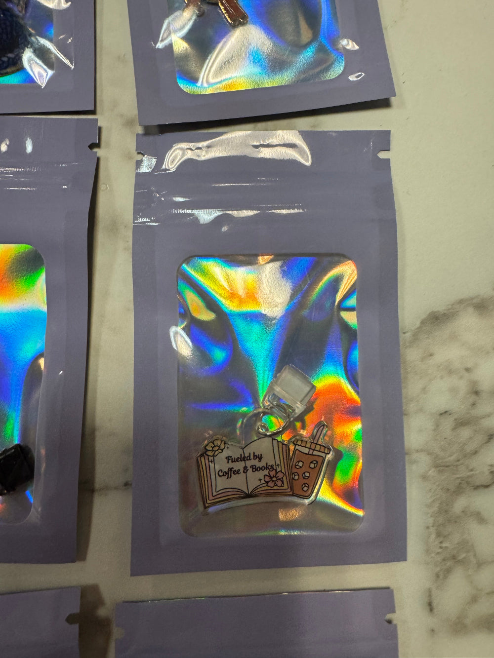 Holographic package with Kindle Charm that says Fueled by Coffee and Books in it