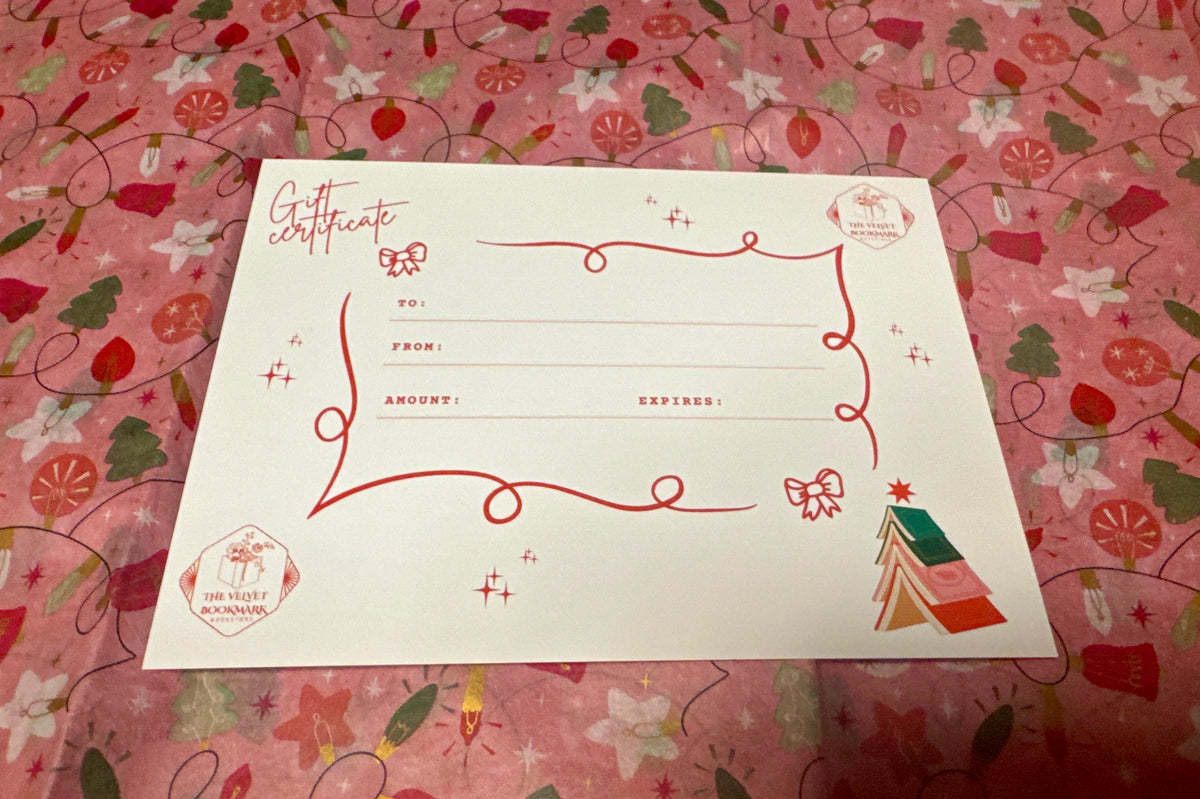 The Velvet Bookmark holiday gift certificate with red cursive text and festive book tree design on pink fabric