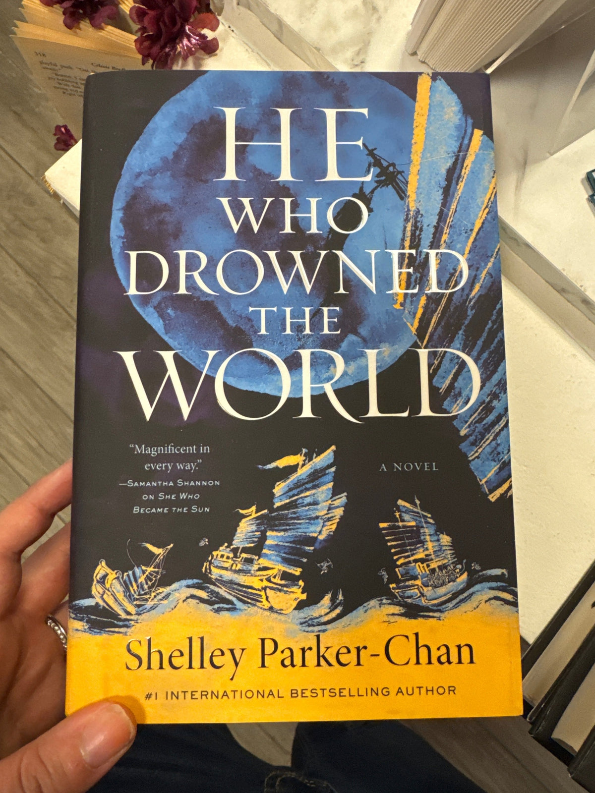 He Who Drowned the World hardcover book by Shelley Parker-Chan with dark blue moon cover art