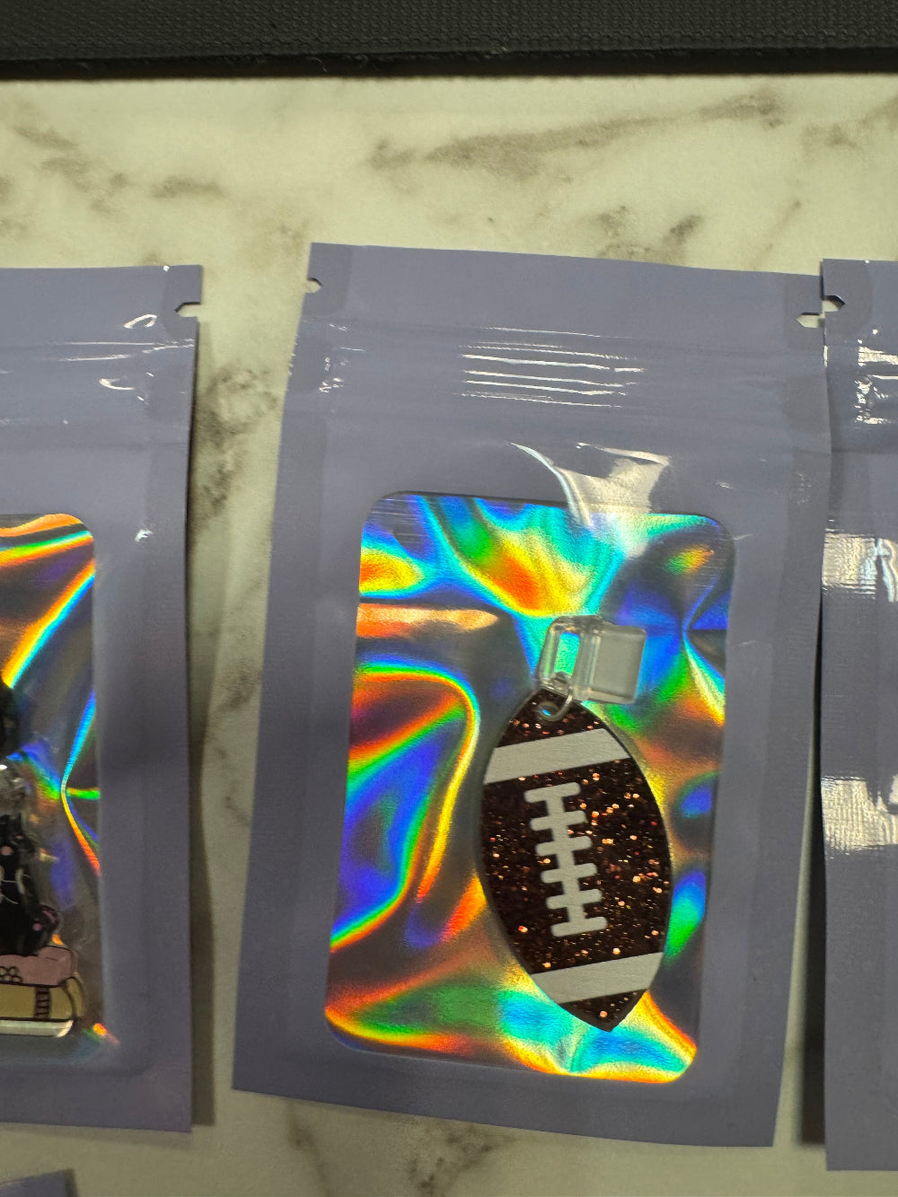 Holographic packaging with sparkly football kindle charm in it