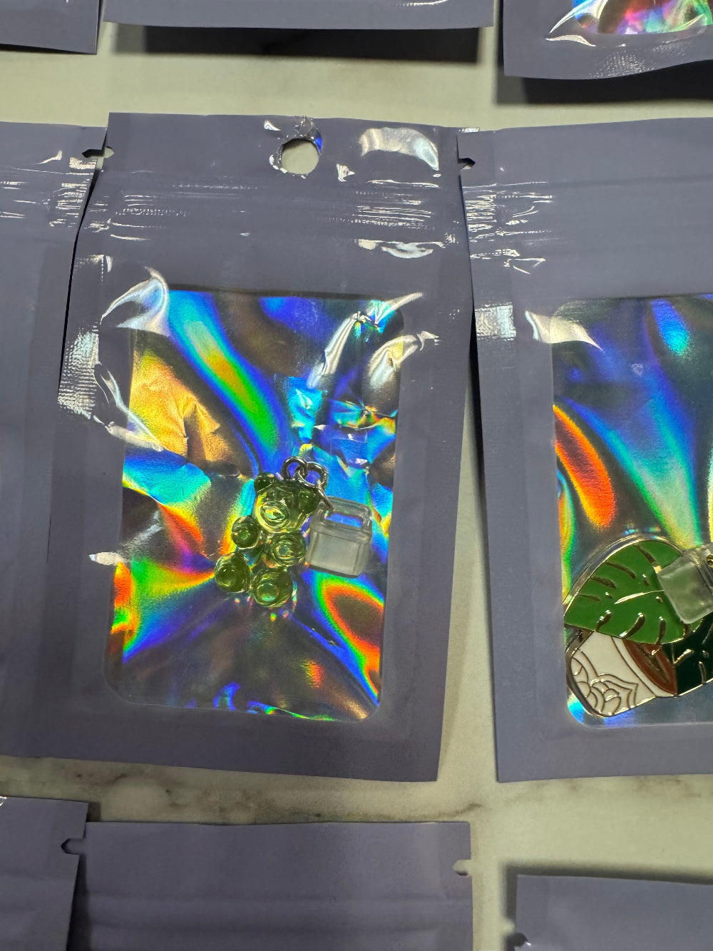 Holographic packaging with green gummy bear kindle charm in it