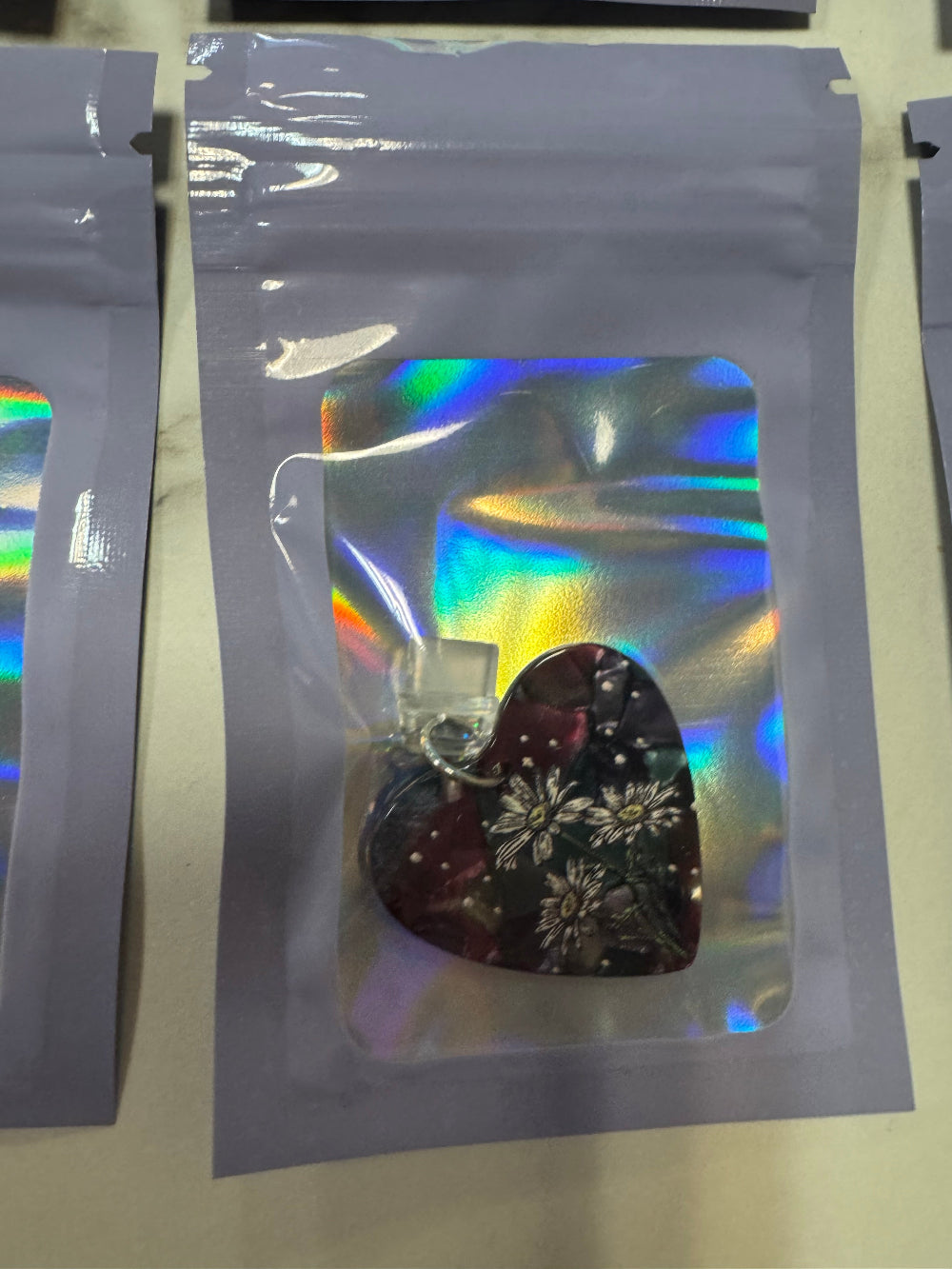 Holographic packaging with floral dark heart kindle charm inside