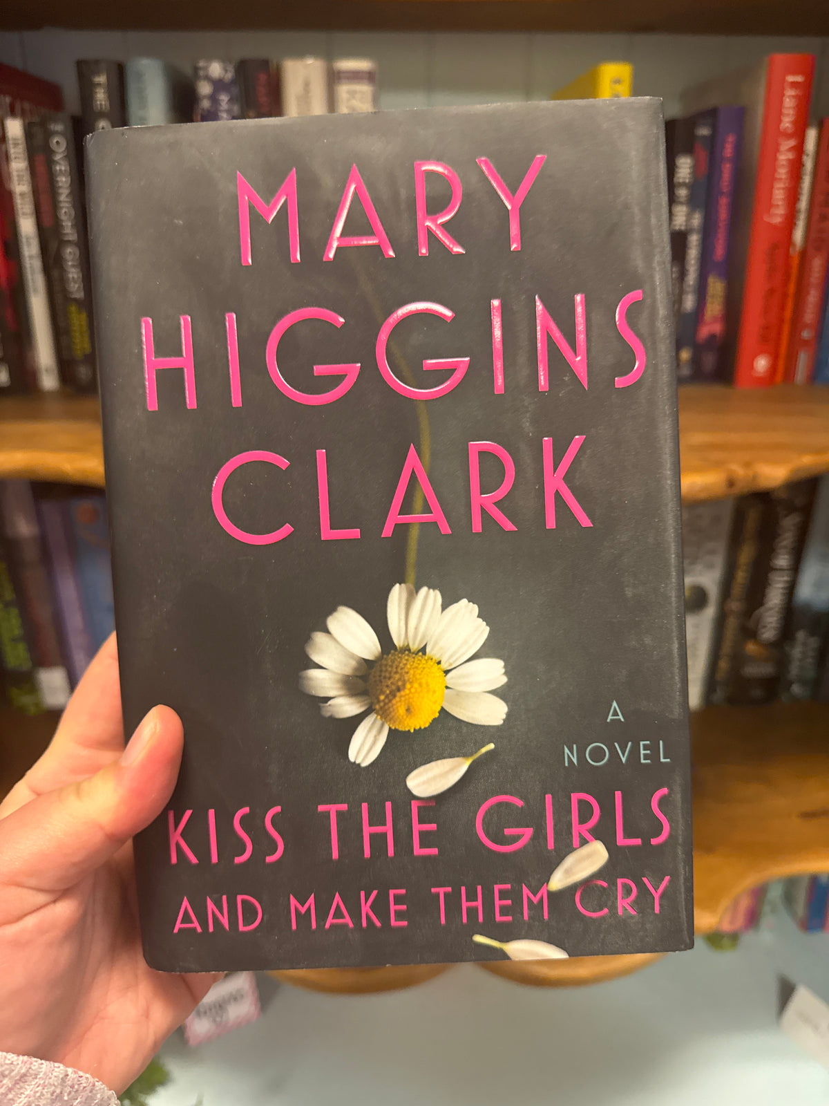 Kiss the Girls and Make Them Cry hardcover novel by Mary Higgins Clark with pink title text and white daisy design