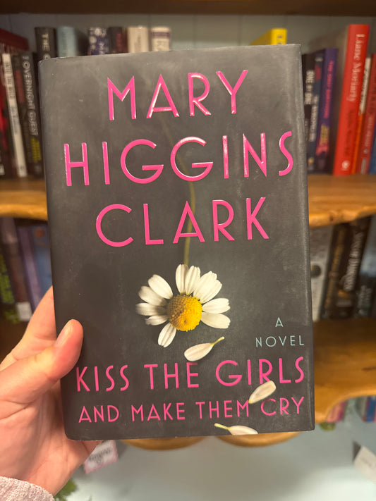 Kiss the Girls and Make Them Cry hardcover novel by Mary Higgins Clark with pink title text and white daisy design