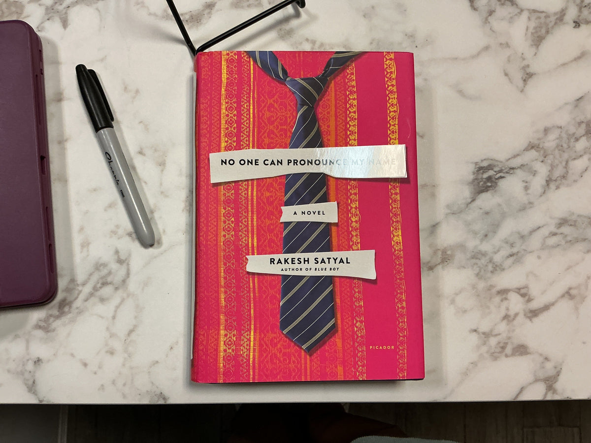 No One Can Pronounce My Name hardcover novel by Rakesh Satyal with pink cover and gold tie design
