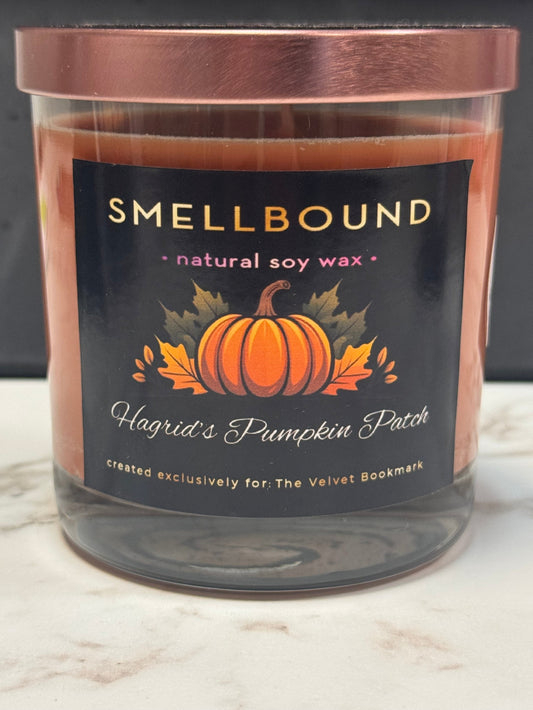Candle with pumpkin design and 'Smellbound' branding on a marble surface