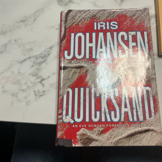 Book titled 'Quicksand' by Iris Johansen on a marble surface