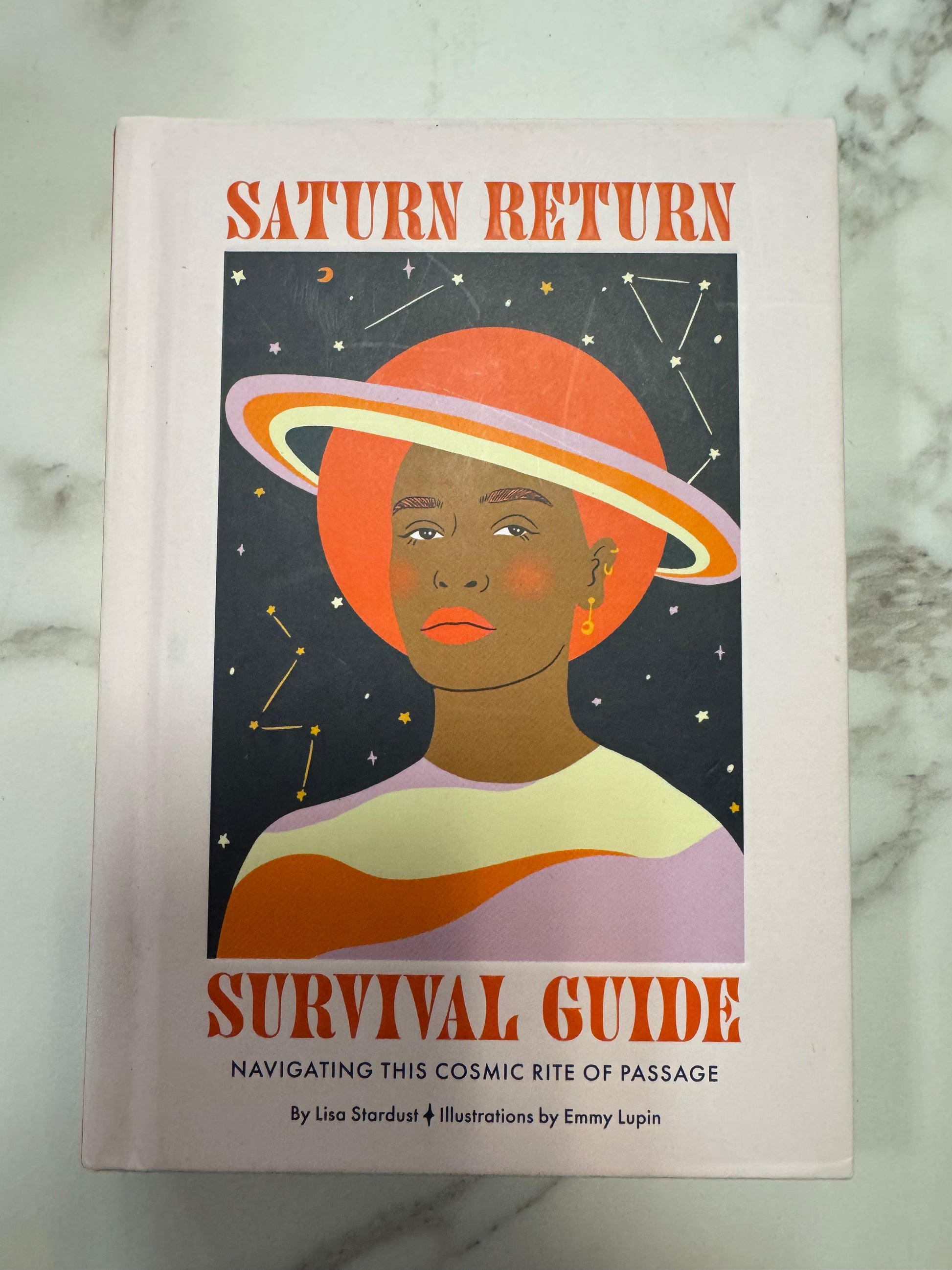 Saturn Return Survival Guide hardcover book by Lisa Stardust with orange serif font and cosmic illustration