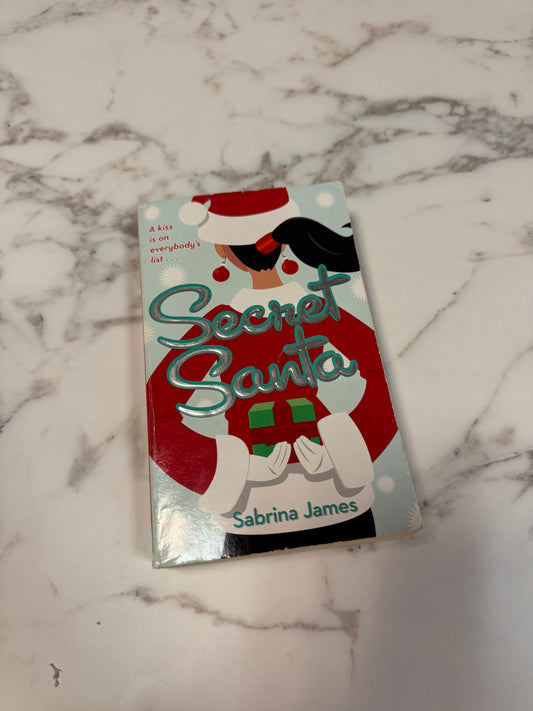 Secret Santa paperback by Sabrina James, festive cover with woman in red sweater and Santa hat