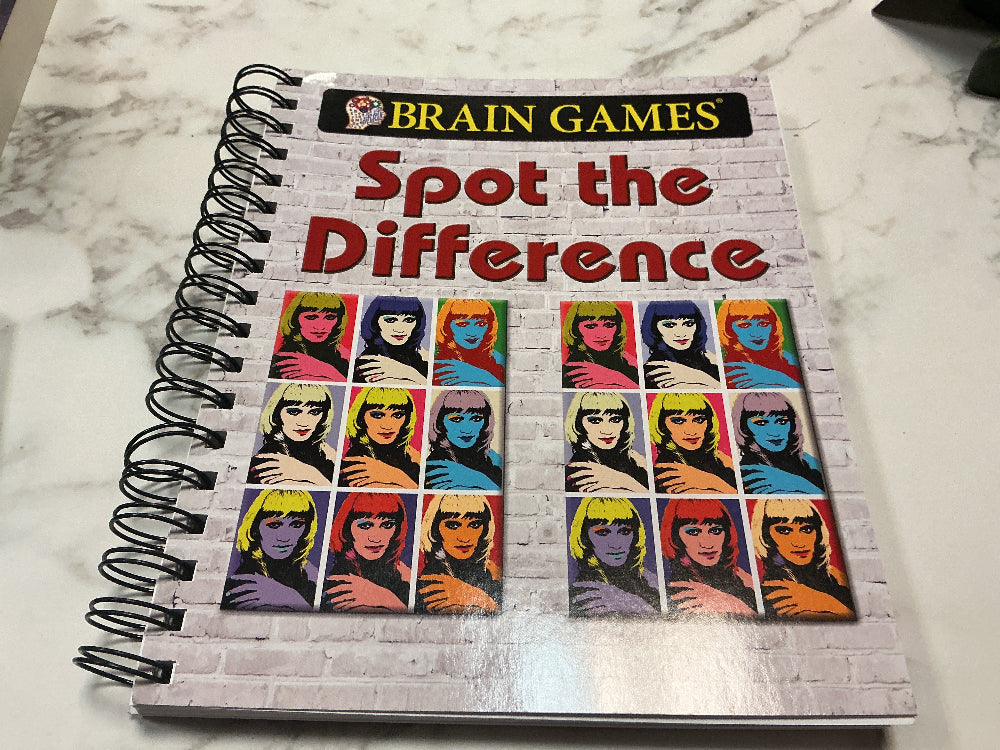 Book titled 'Brain Games Spot the Difference' on a marble surface