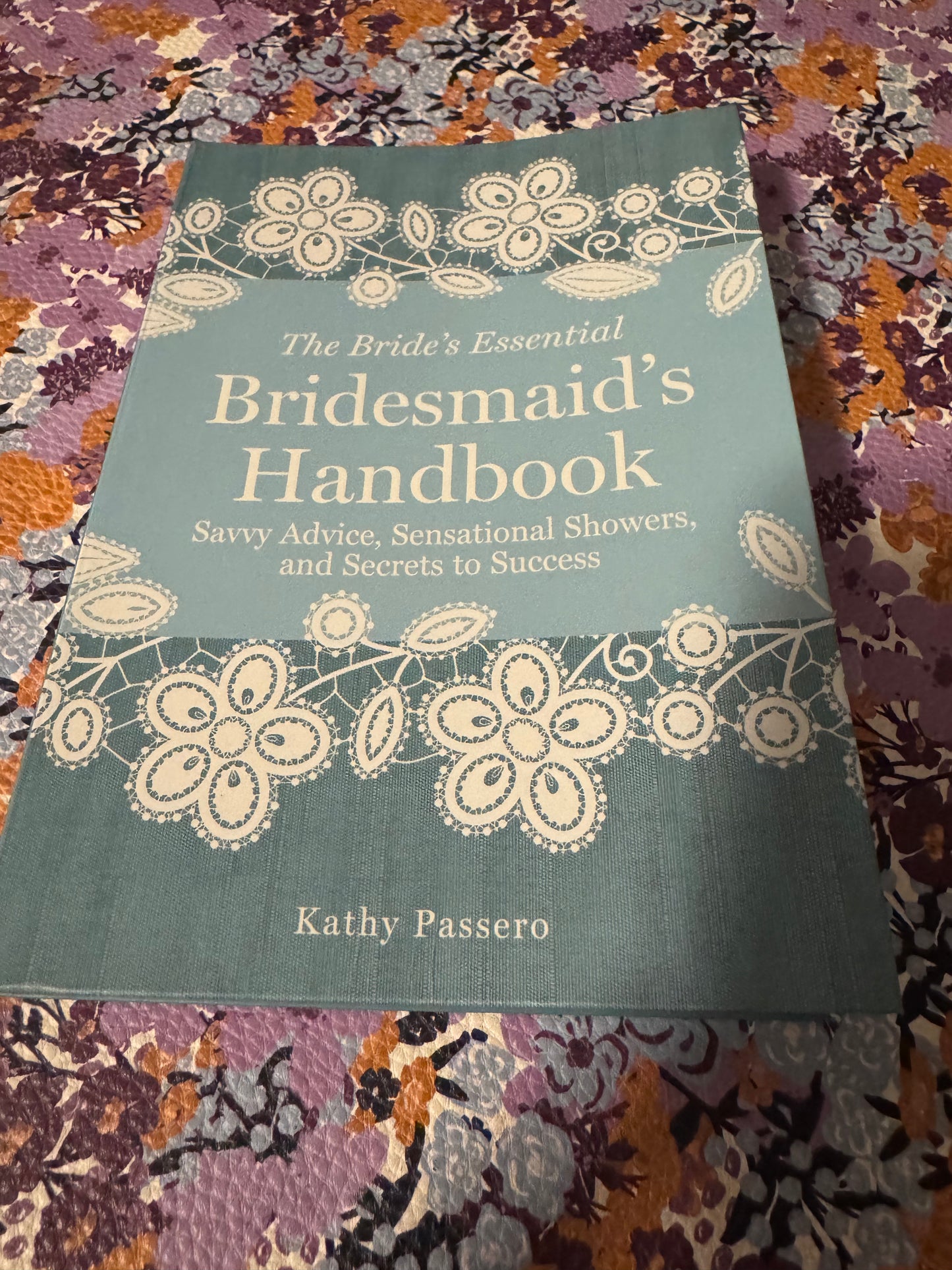 The Bride's Essential Bridesmaid's Handbook teal hardcover book with white lace floral design