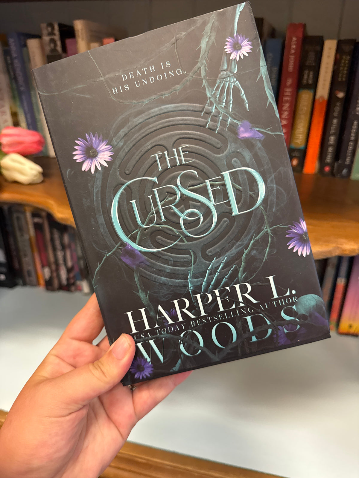 The Cursed hardcover book by Harper L. Woods with dark grey cover and teal maze design