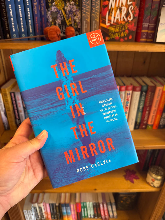 The Girl in the Mirror hardcover book by Rose Carlyle with blue cover and girl silhouette