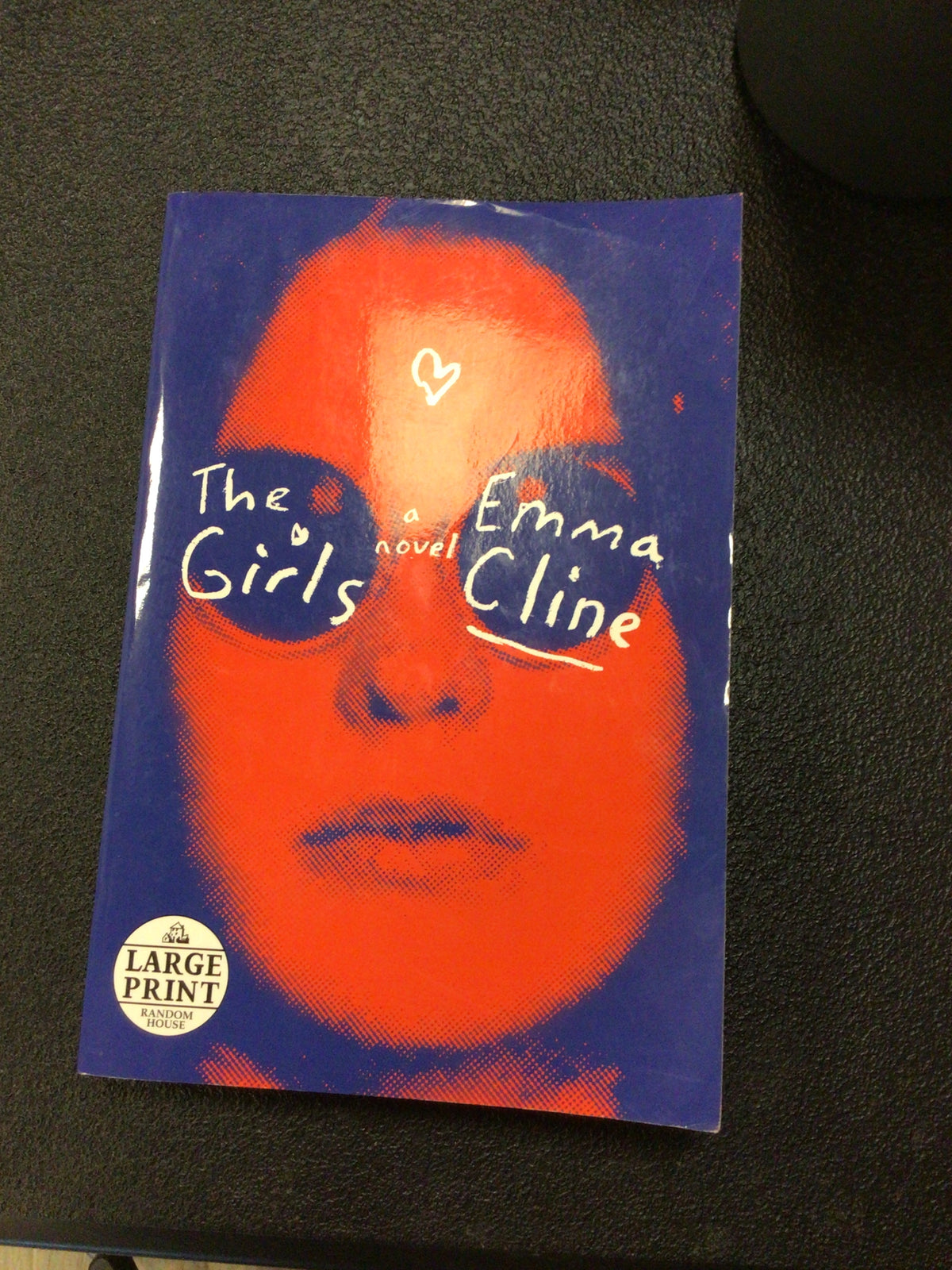 The Girls paperback novel by Emma Cline, large print edition with red halftone cover art and Random House sticker