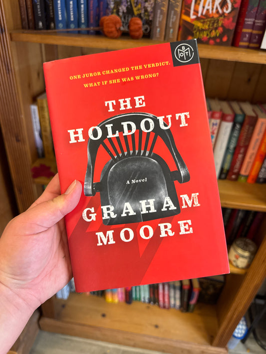 The Holdout hardcover book by Graham Moore with black chair cover art