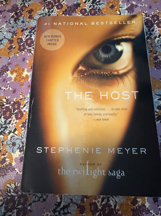The Host paperback by Stephenie Meyer with blue eye cover design on floral fabric