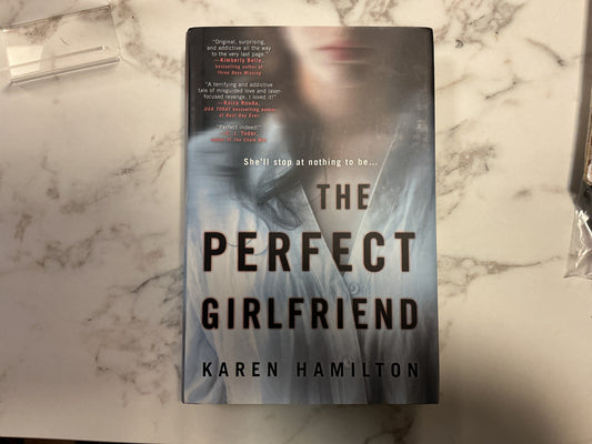 The Perfect Girlfriend hardcover book by Karen Hamilton on marble surface