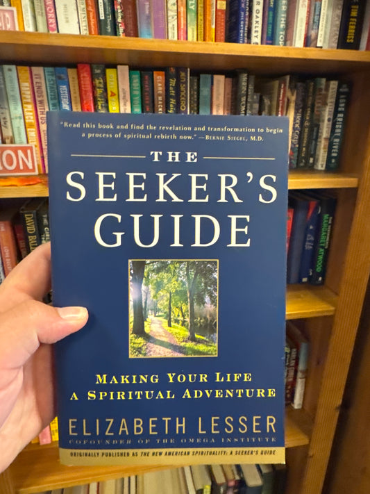 Navy blue hardcover book The Seeker's Guide by Elizabeth Lesser with gold lettering and forest path cover art