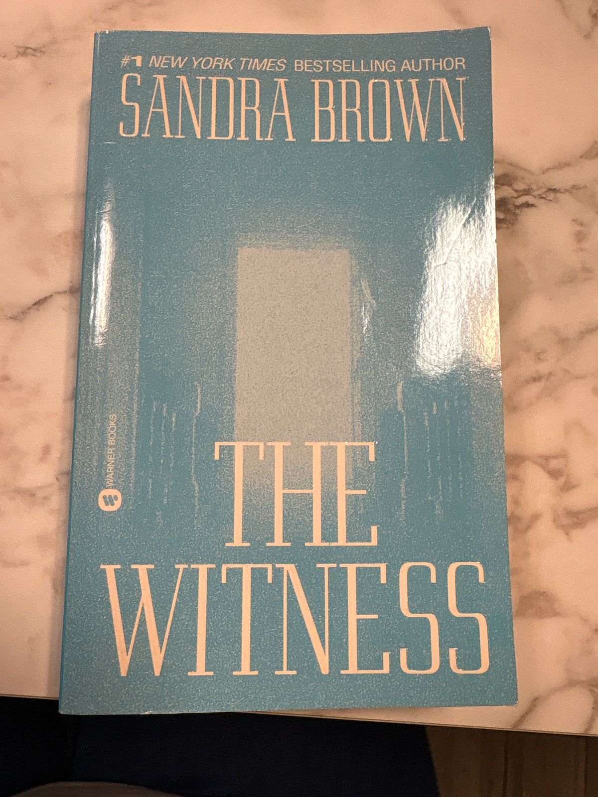 The Witness paperback novel by Sandra Brown, teal cover with peach title and abstract graphic design