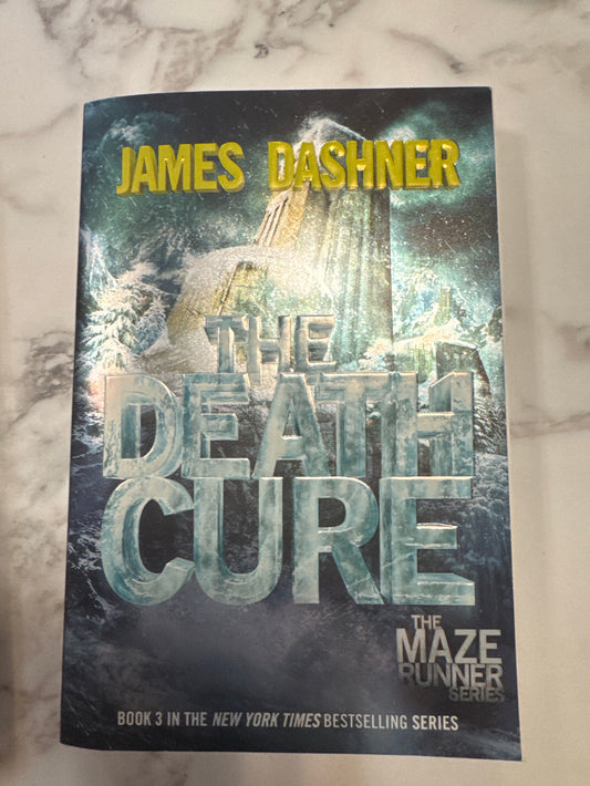 Book titled 'The Death Cure' by James Dashner on a marble surface
