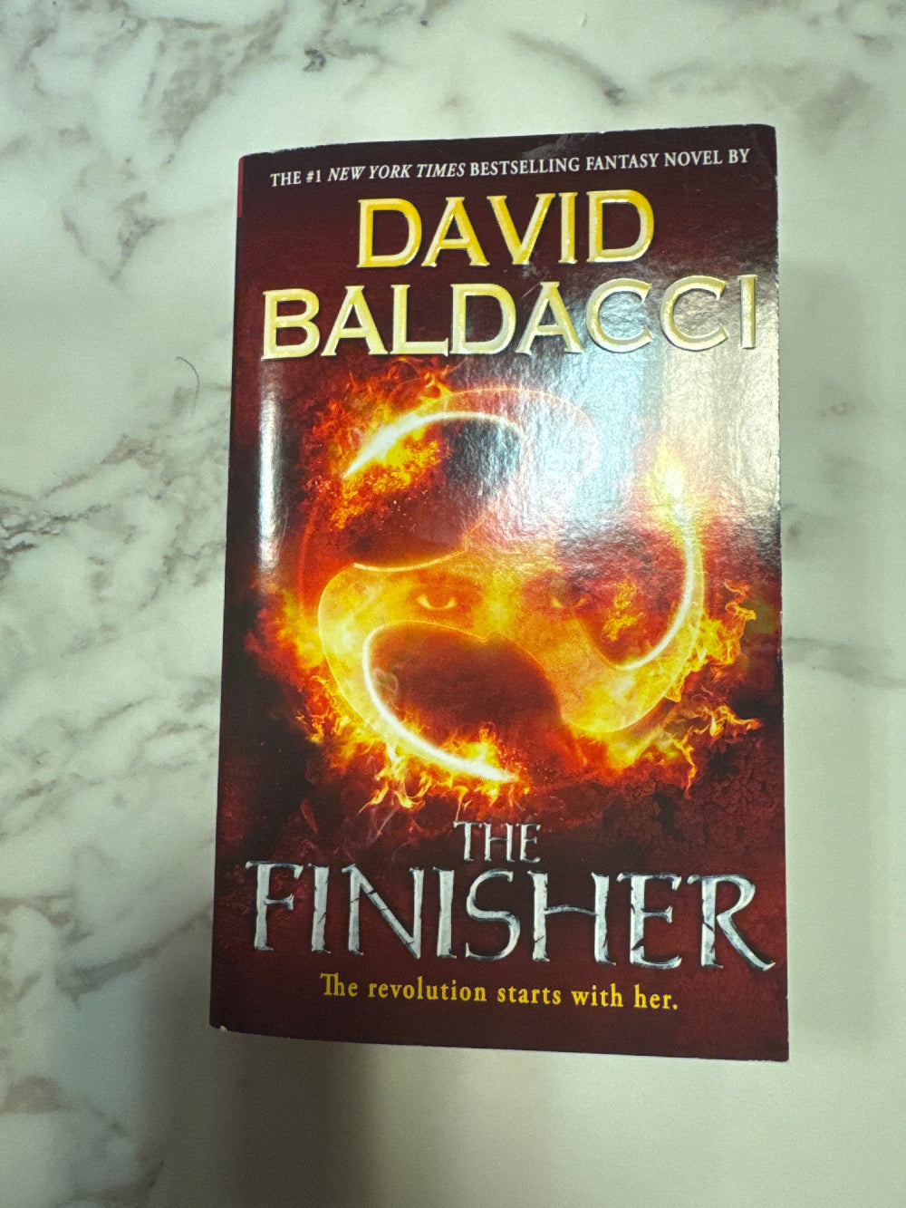 Book titled 'The Finisher' by David Baldacci on a marble surface